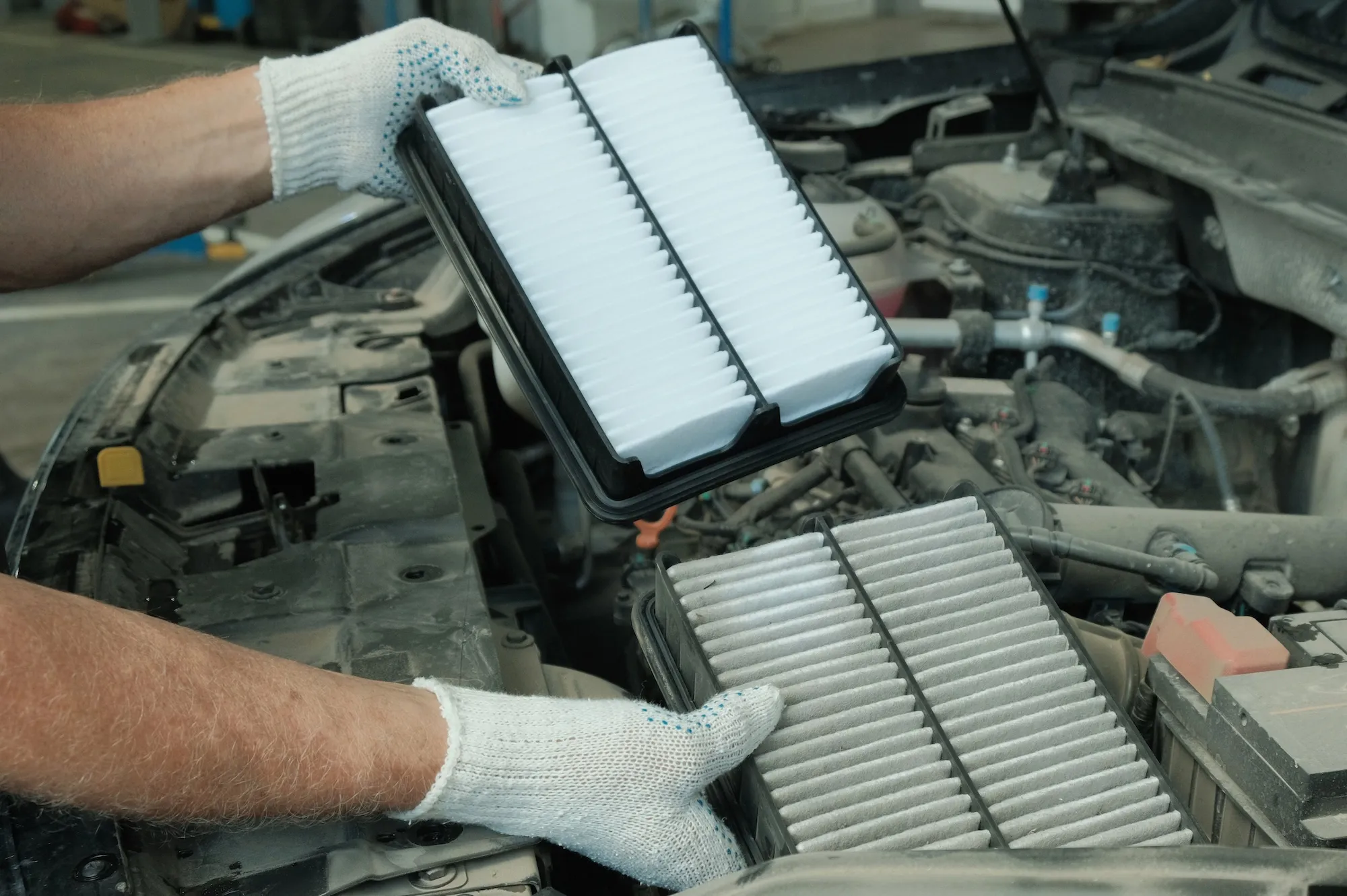 a clean and dirty car air filter side by side in the engine bay