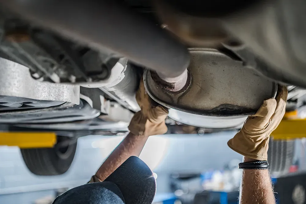 mechanic inspecting an exhaust manifold for cracks and leaks